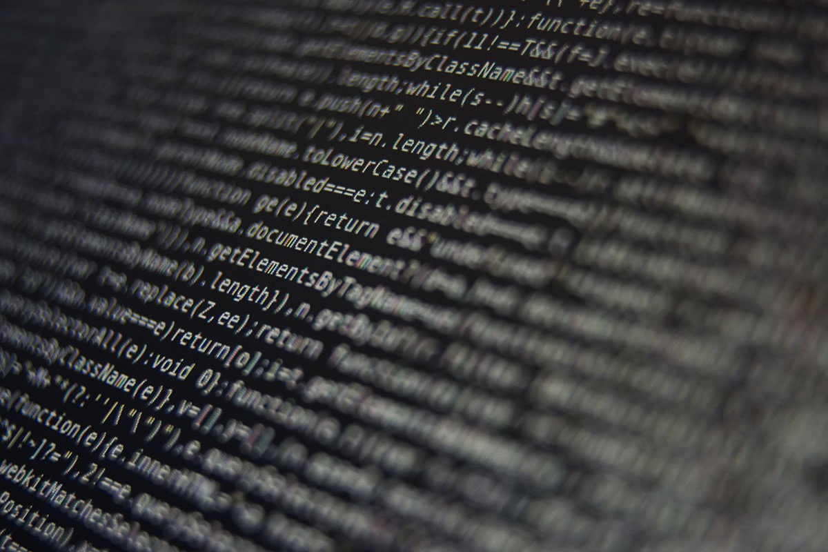 Close-up of lines of JavaScript source code on a dark monitor, angled and softly out of focus toward the edges